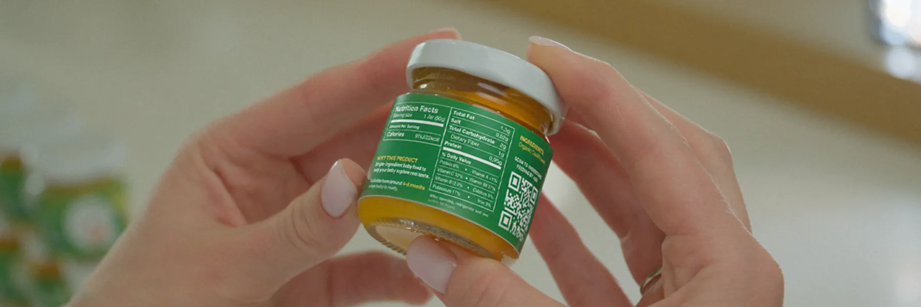 Hands holding a PurEats jar, turned to show the nutrition facts and ingredients on the back label